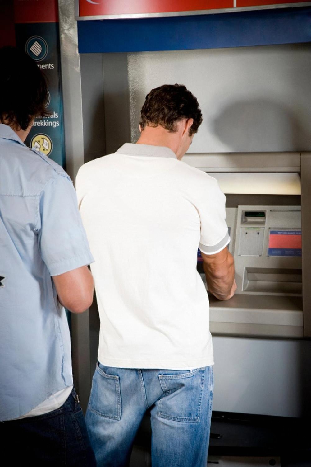 Two customers using an ATM at a UAE bank while others wait for service